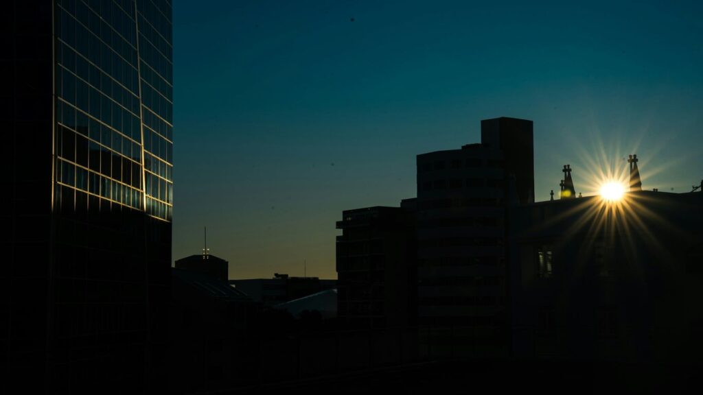 Sunburst over city buildings at dusk