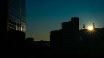 Sunburst over city buildings at dusk