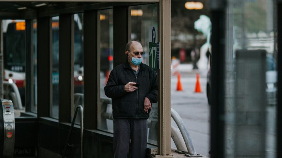 man in black suit jacket and black pants standing beside glass window