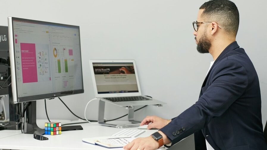 a man sitting at a desk with a laptop and a computer