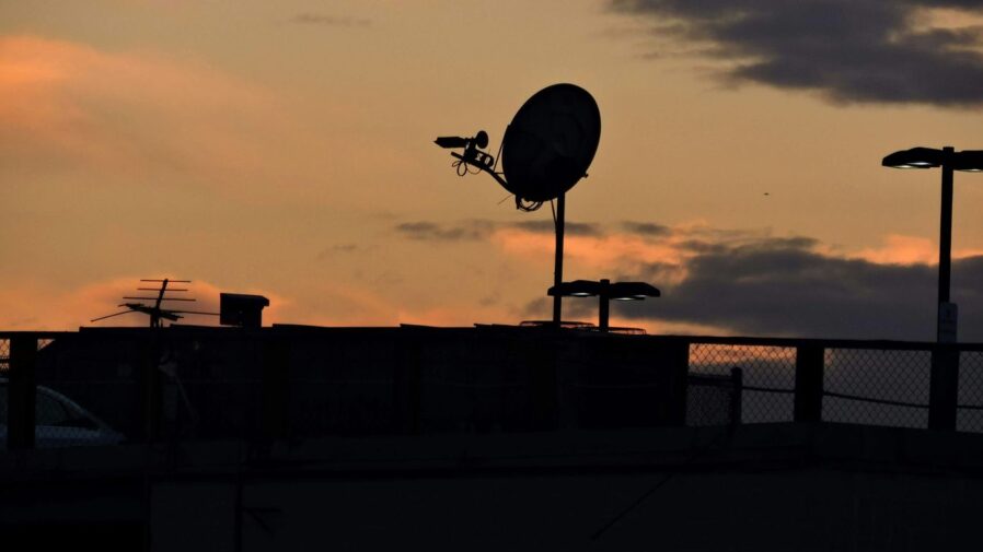 a satellite dish on top of a building at sunset