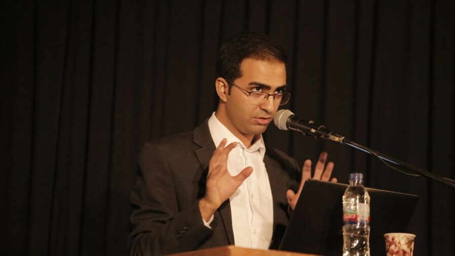 a man in a suit and tie speaking into a microphone