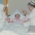 a woman in a hospital bed being assisted by a nurse