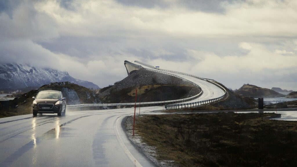 a car driving down a wet road with mountains in the background
