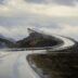 a car driving down a wet road with mountains in the background