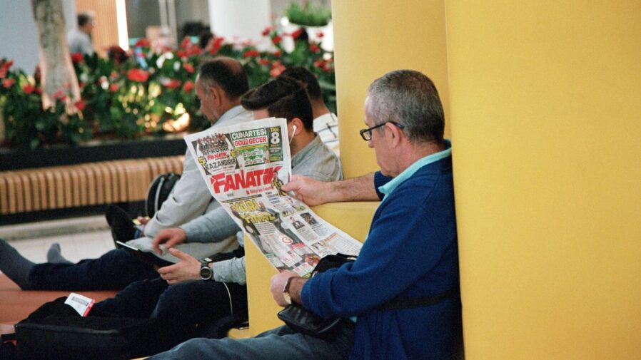 a man sitting on a bench reading a newspaper