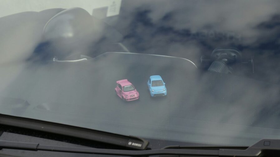 Two small toy cars on a dashboard.