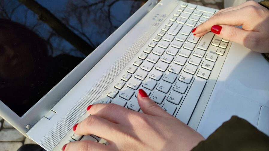 a woman is typing on a laptop outside