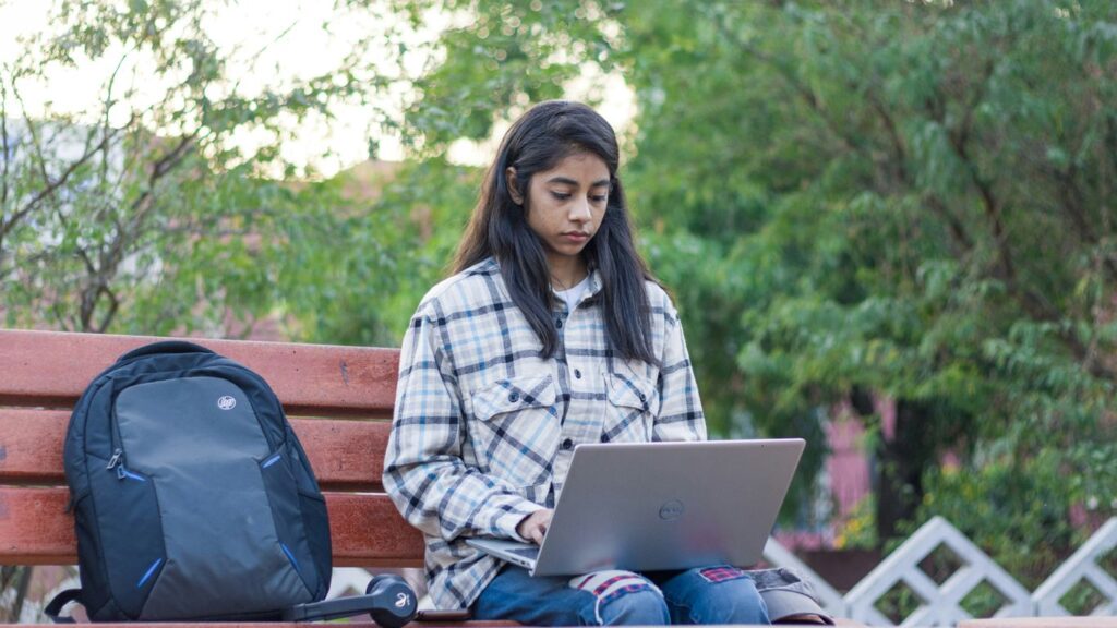 a woman sitting on a bench using a laptop