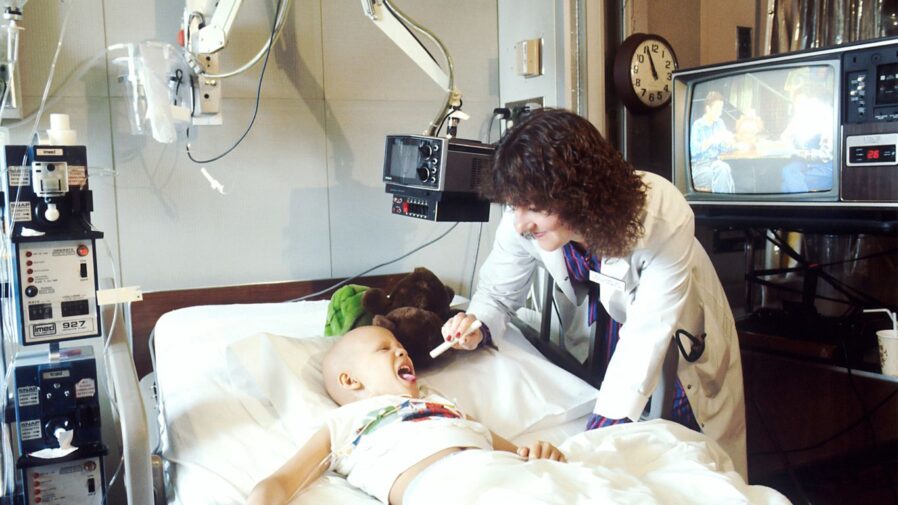 child lying on bed while doctor checking his mouth