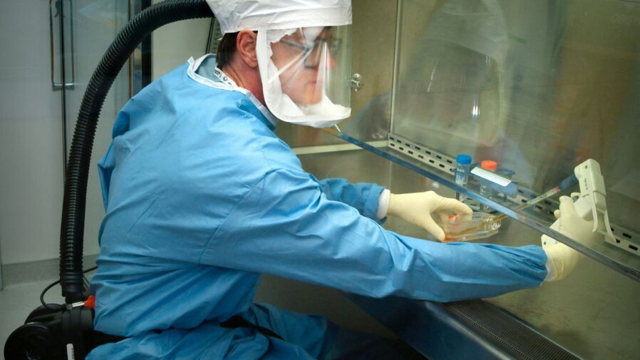 a man in a protective suit and mask working on a machine