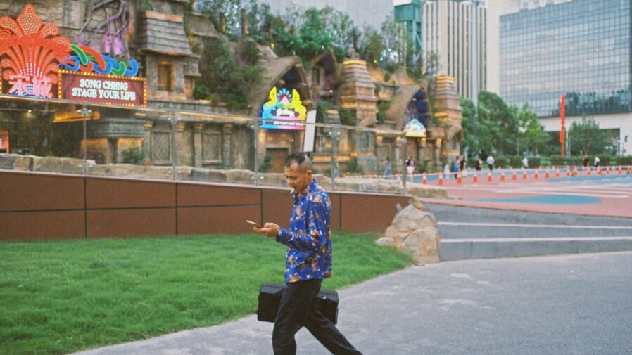 man in blue and white button up shirt and black pants holding yellow plastic bucket