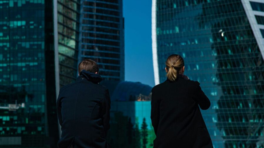 a man and a woman sitting on a ledge looking at the city