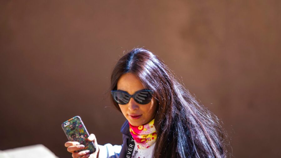 woman in white and pink jacket holding iphone