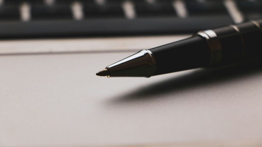a pen sitting on top of a paper next to a keyboard