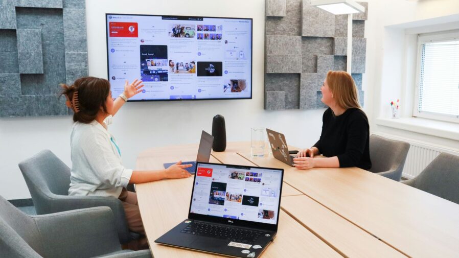 two women sitting at a table with a laptop