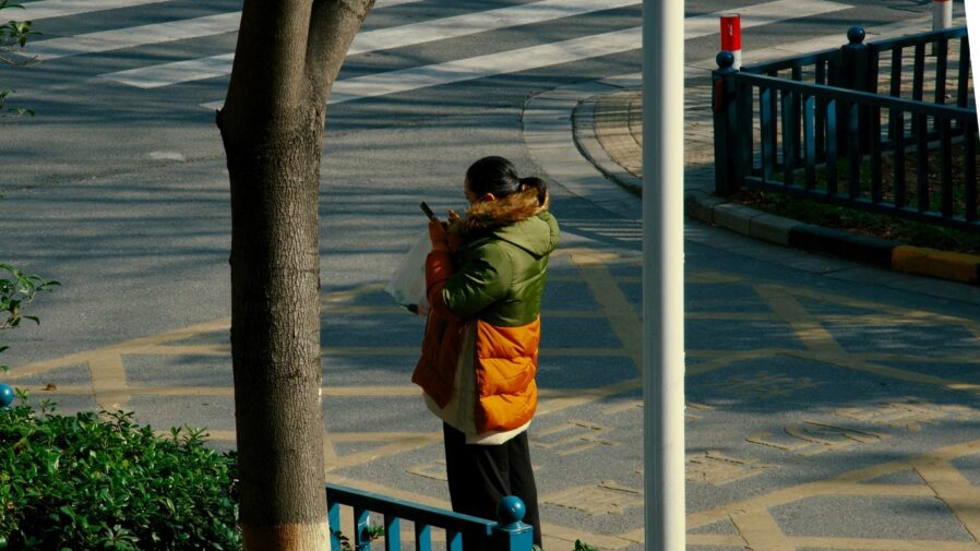a woman standing on a street corner holding a cell phone