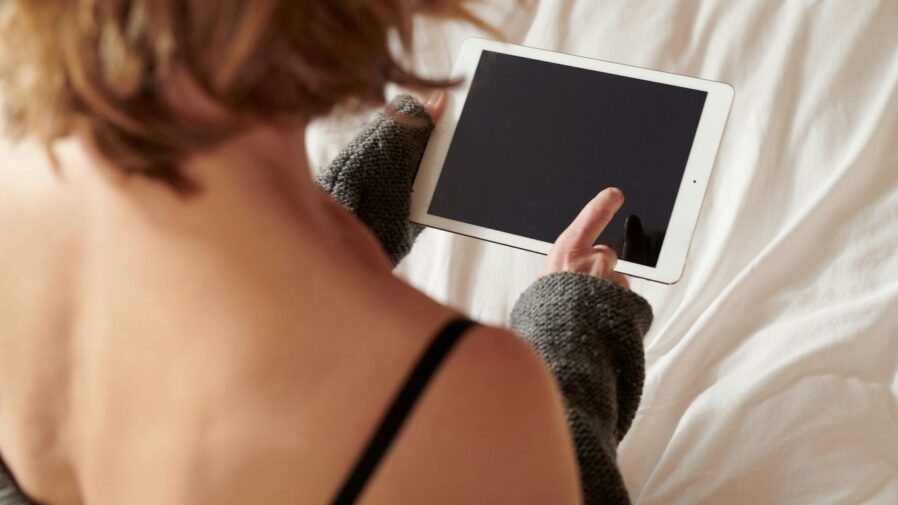 woman in black brassiere holding white ipad