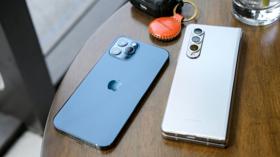 two cell phones sitting on top of a wooden table