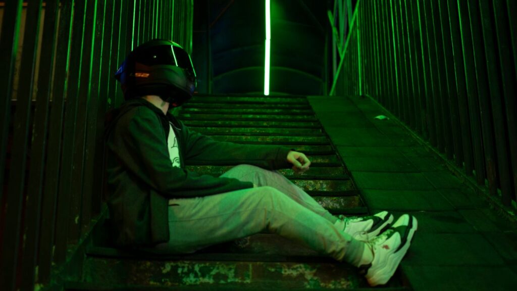 A man wearing a helmet sitting on a ledge