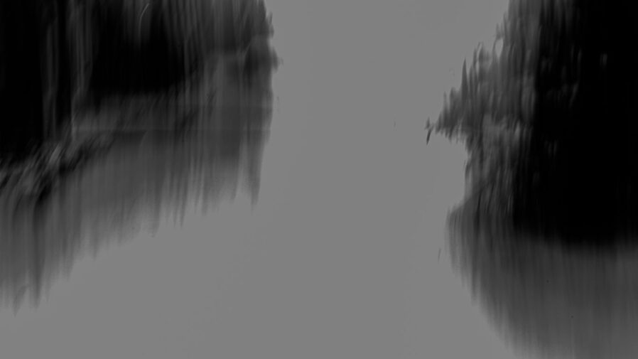 Blurred trees appear over water.