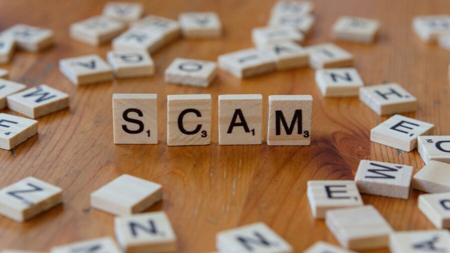 Scam spelled with scrabbles on a wooden table
