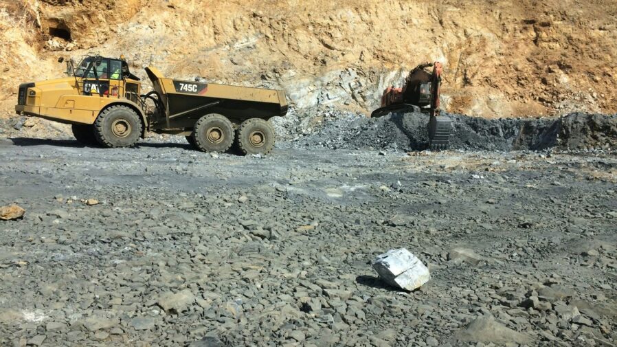 yellow heavy equipment filled with stone by back-hoe
