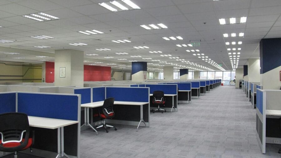 an empty office cubicle with chairs and desks