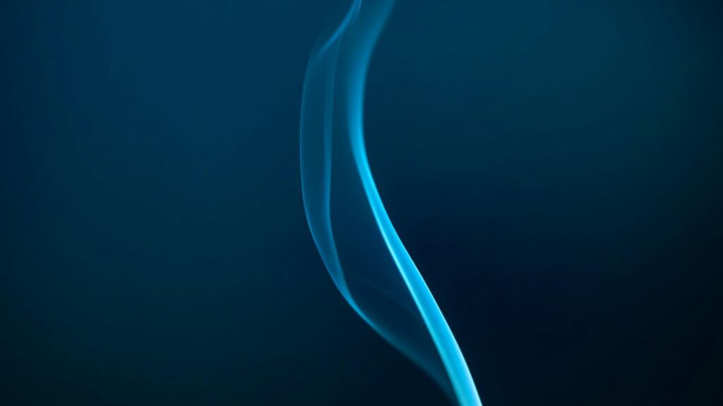 Blue smoke gracefully rising against the dark.