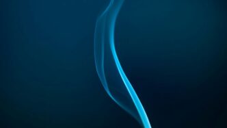 Blue smoke gracefully rising against the dark.