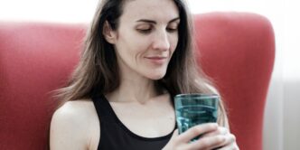 a woman sitting in a red chair holding a glass