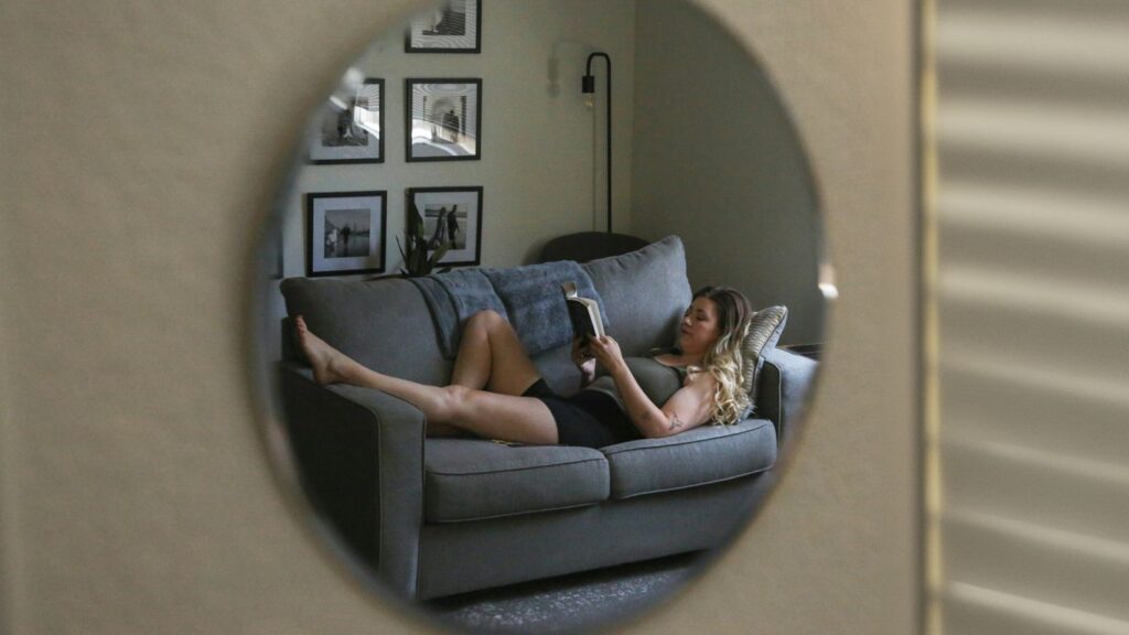 A woman laying on a couch reading a book