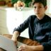 a man sitting at a table using a laptop computer
