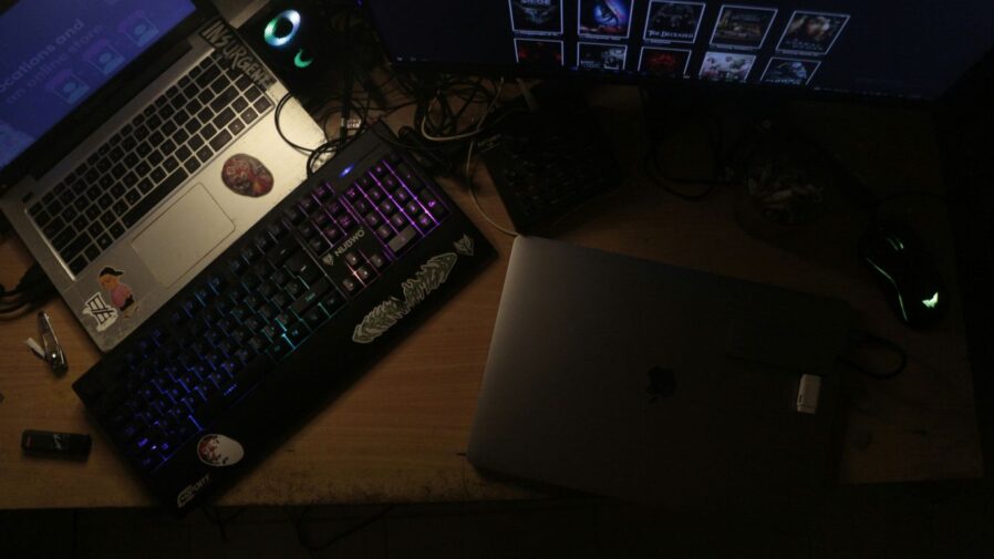 Two laptops and a keyboard on a desk.
