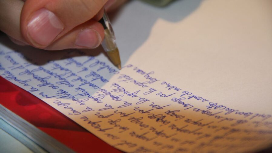 a person writing on a piece of paper with a pen