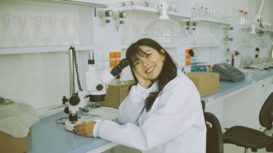 woman in white laboratory gown holding black microphone