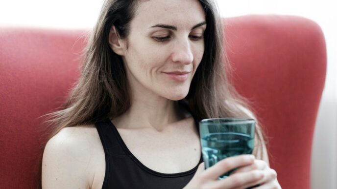 a woman sitting in a red chair holding a glass