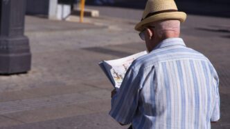 a man in a hat is reading a newspaper
