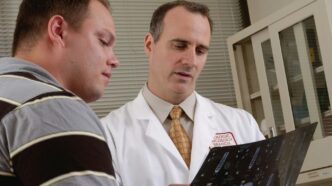 man in white dress shirt holding black tablet computer