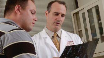 man in white dress shirt holding black tablet computer