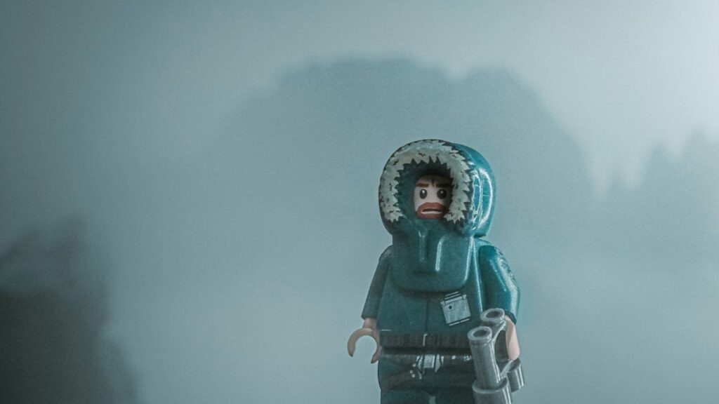 a lego figure with a hood on standing in the fog