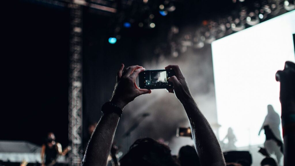 person taking photo of people performing on stage