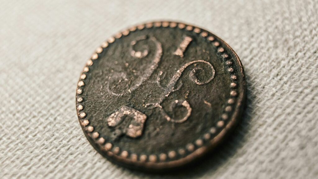 silver round coin on white textile