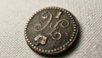 silver round coin on white textile