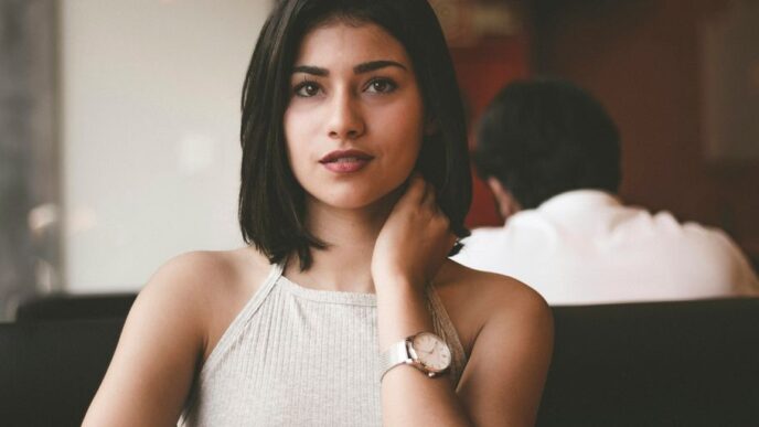 woman wearing gray spaghetti strap shirt sitting on black leather sofa close-up photo