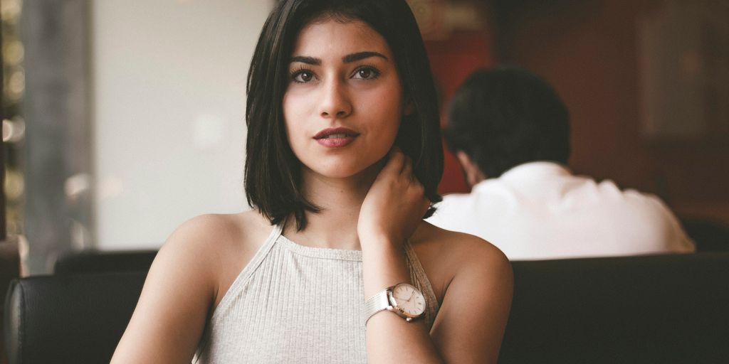 woman wearing gray spaghetti strap shirt sitting on black leather sofa close-up photo