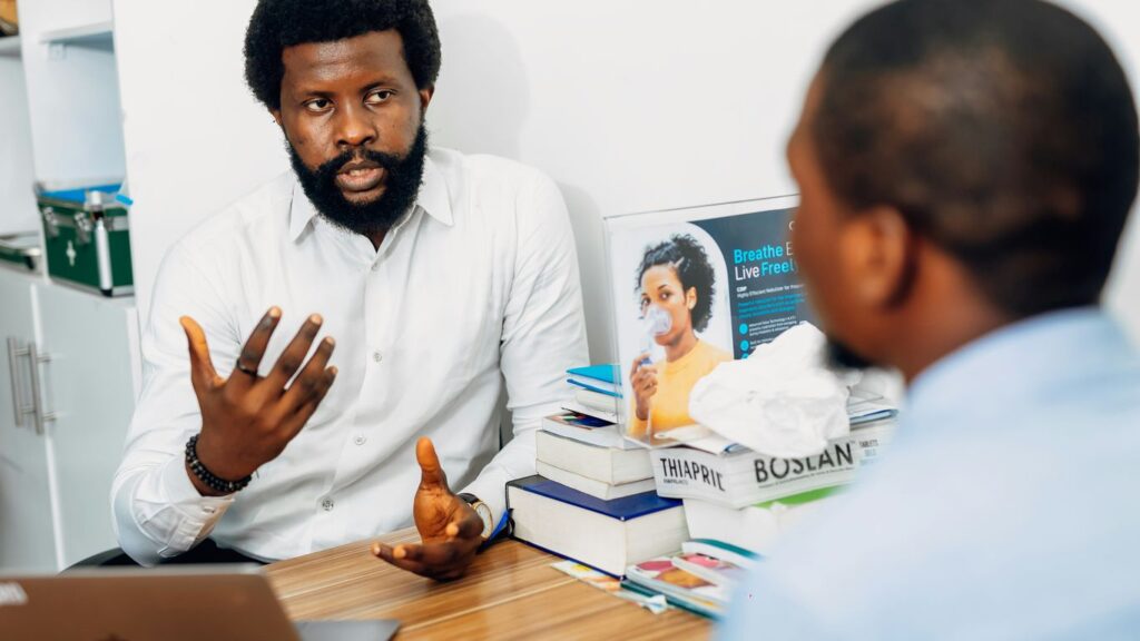 A man sitting at a desk talking to another man