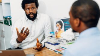 A man sitting at a desk talking to another man