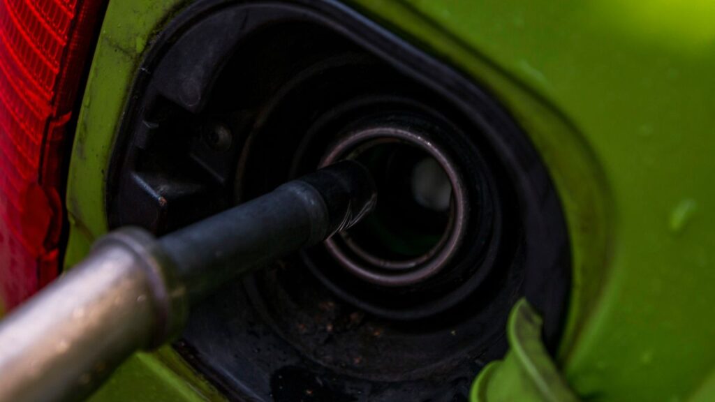A close up of a green car with a gas nozzle