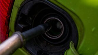 A close up of a green car with a gas nozzle